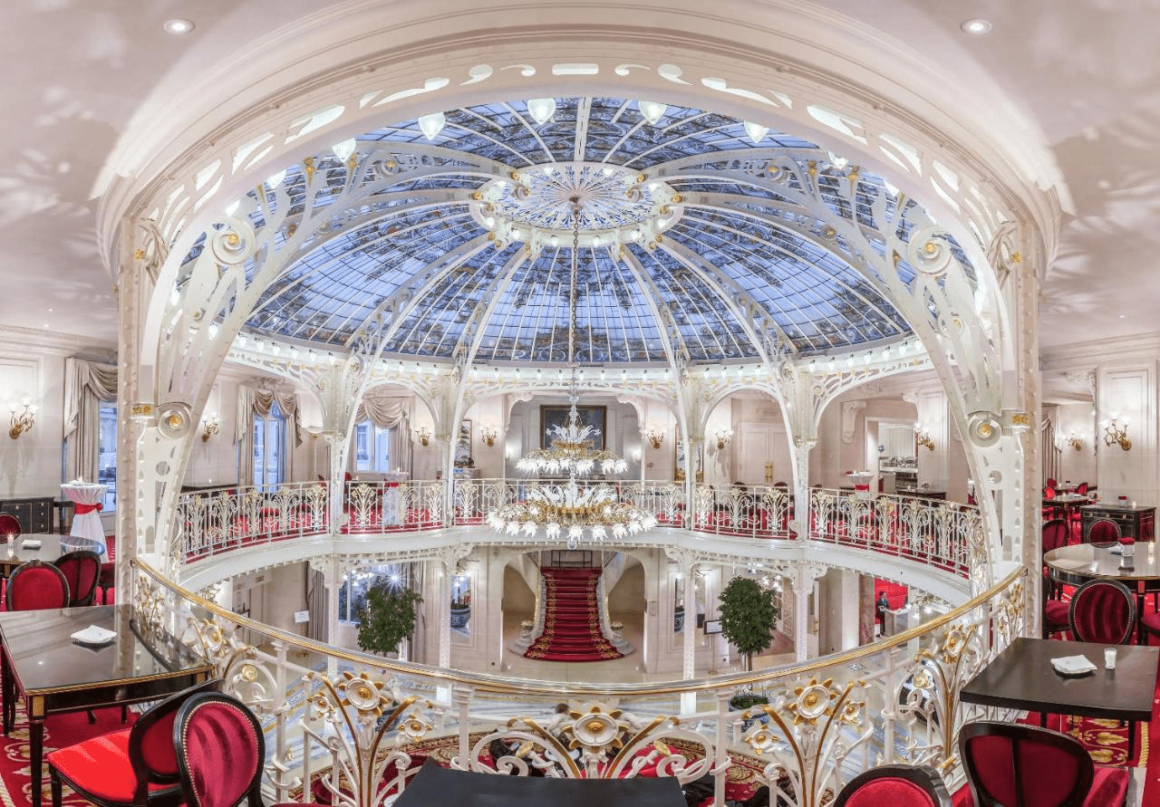 "Indrukwekkende inkomhal van een luxe hotel in Monaco, gedomineerd door een enorme kristallen luchter die de ruimte prachtig verlicht."