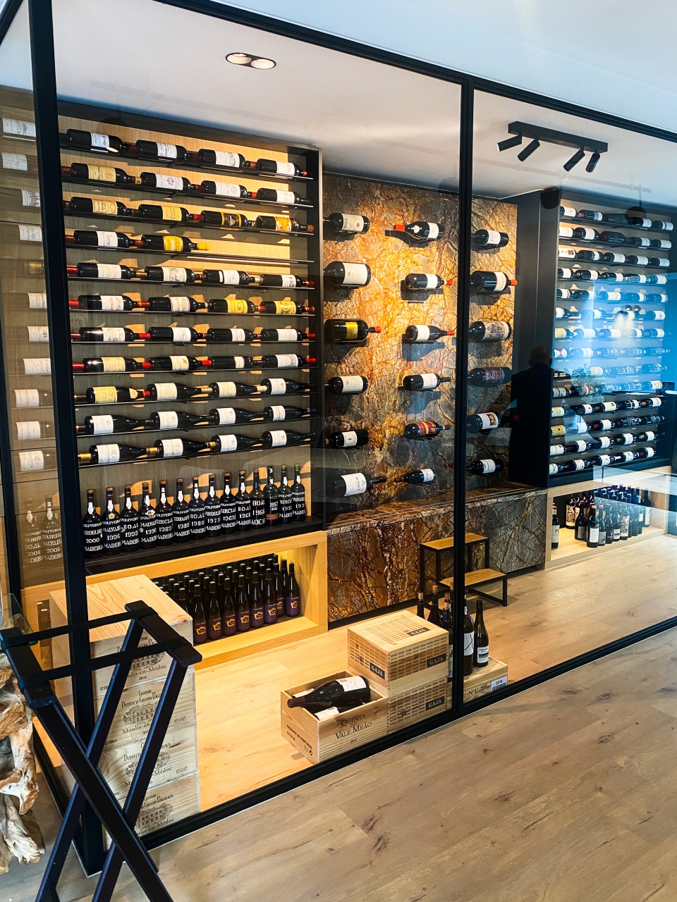 An impressive, well-lit wine storage cabinet in restaurant De Bakermat, filled with an extensive selection of high-quality wines, acting as an elegant eye-catcher in the sleek, modern interior.