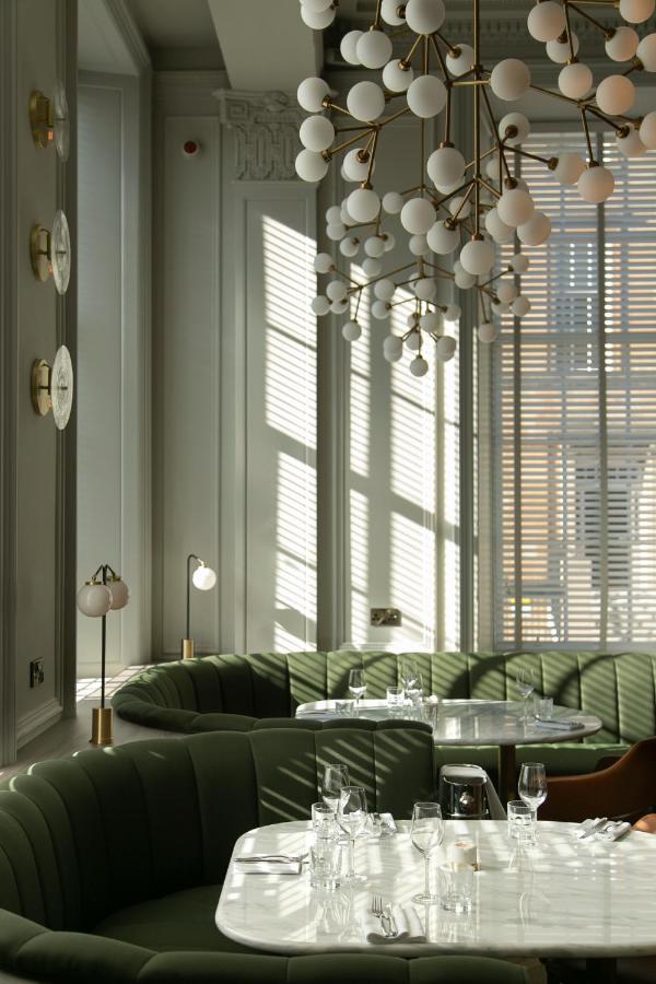 An inviting image of the Kimpton Blythswood Square Hotel's lobby, showcasing its elegant mix of modern design elements and historical opulence, with plush furnishings and warm ambient lighting.