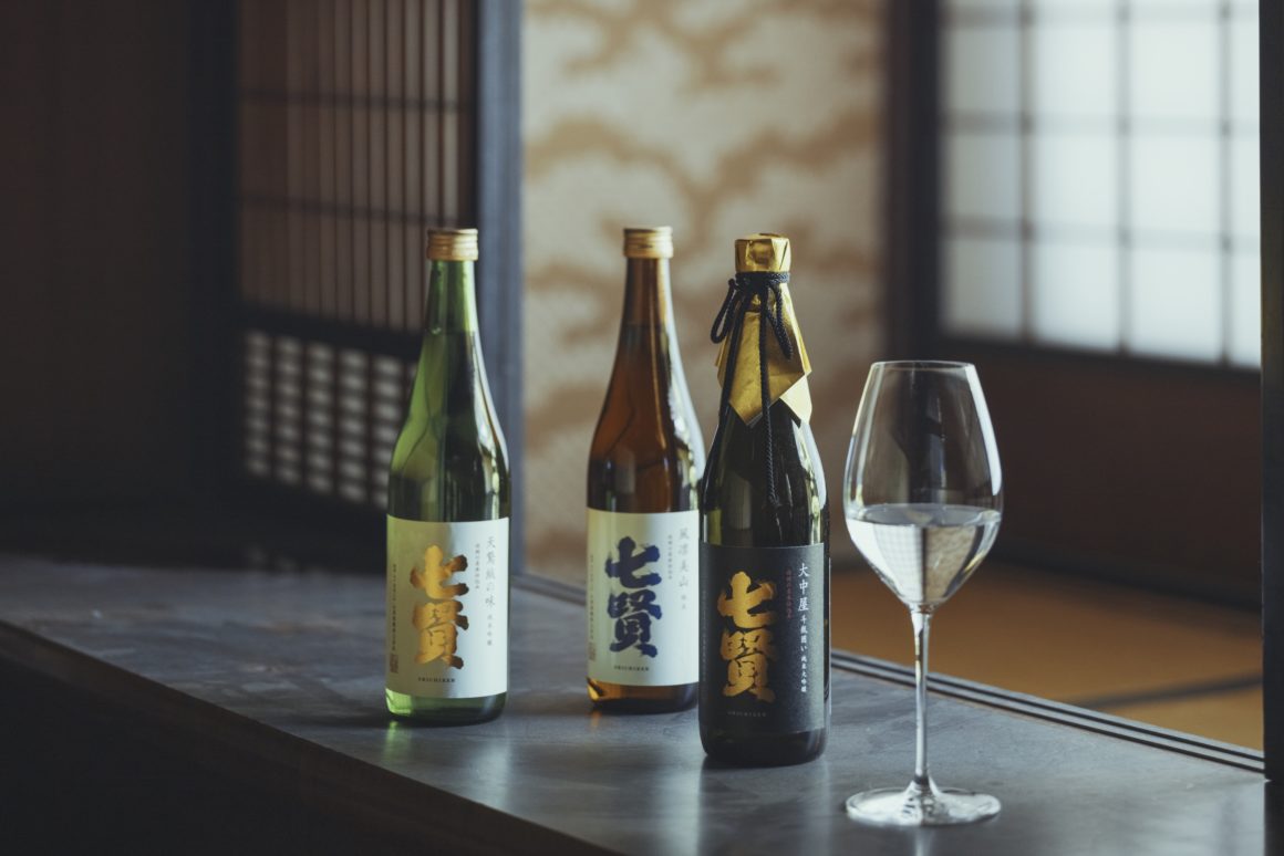 Drie flessen Shichiken sake uitgestald op een tafel, klaar voor degustatie.