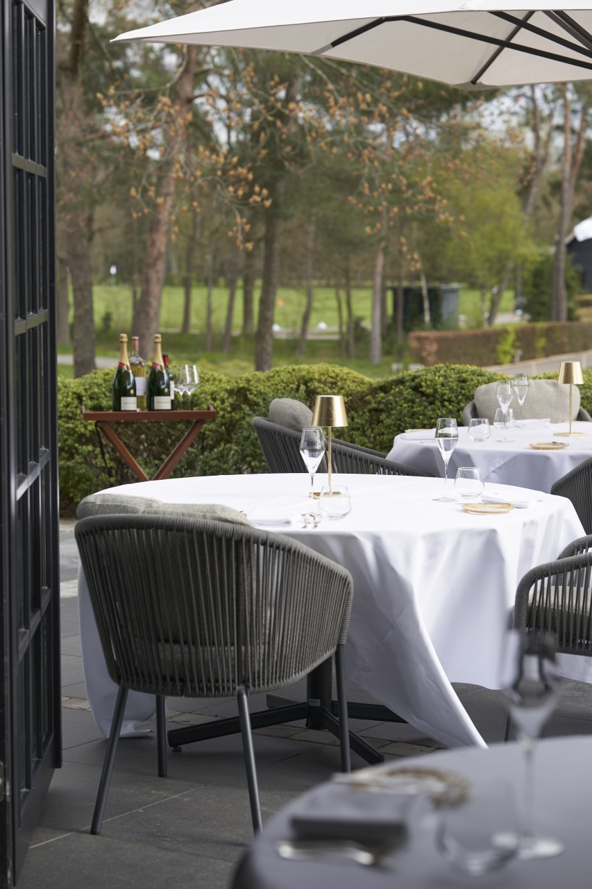 Atmospheric terrace of restaurant The Charles, surrounded by the greenery of nature reserve De Maashorst, ideal for outdoor culinary experiences.